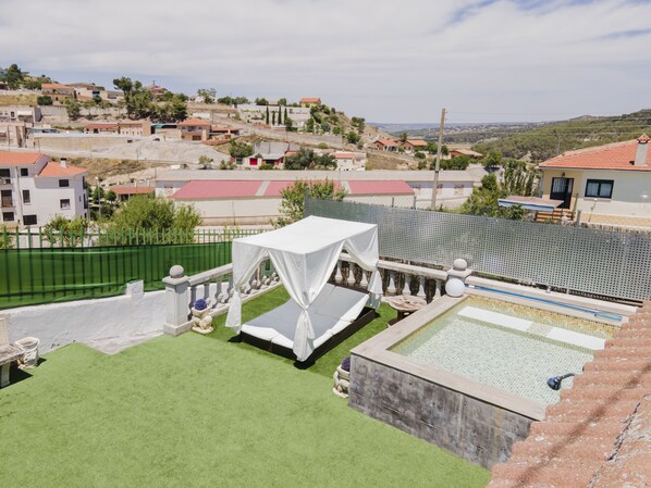 Un espace piscine sur le toit, doté d’un auvent blanc et offrant une vue sur un quartier résidentiel.