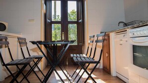 Une cuisine équipée d’une table et de chaises, d’un lave-linge et d’une fenêtre donnant sur un espace verdoyant.