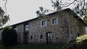 Un bâtiment en pierre doté de nombreuses fenêtres et portes, entouré de verdure.