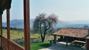 A covered outdoor area with a stone floor, a wooden bench, and a picnic table. - Rural apartment El Mirador de Cazanes for 4 people (Villaviciosa)