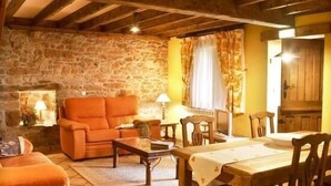 A rustic room with a stone wall, wooden furniture, and a cozy atmosphere. - Rural apartment El Mirador de Cazanes for 4 people (Villaviciosa)