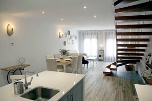 Eine moderne Küche mit Spüle, Essbereich mit Stühlen und einer Treppe.