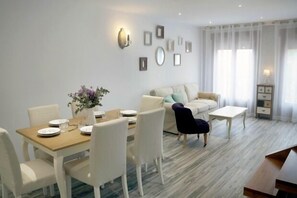 Ein modernes Wohnzimmer mit Essbereich, ausgestattet mit einer Couch, einem Couchtisch und einem Esstisch für vier Personen.