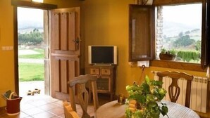 A cozy room with a wooden ceiling, a television, a chair, a table, and a window with a view of the countryside. - Rural apartment El Mirador de Cazanes for 2 people (Villaviciosa)