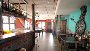 Uma área de bar com mesa de bilhar, banquetas e balcão.