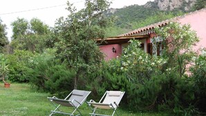 A garden with two lounge chairs and a building with a red roof. - L'AGLIENTU CALLA ROOM (Loiri)