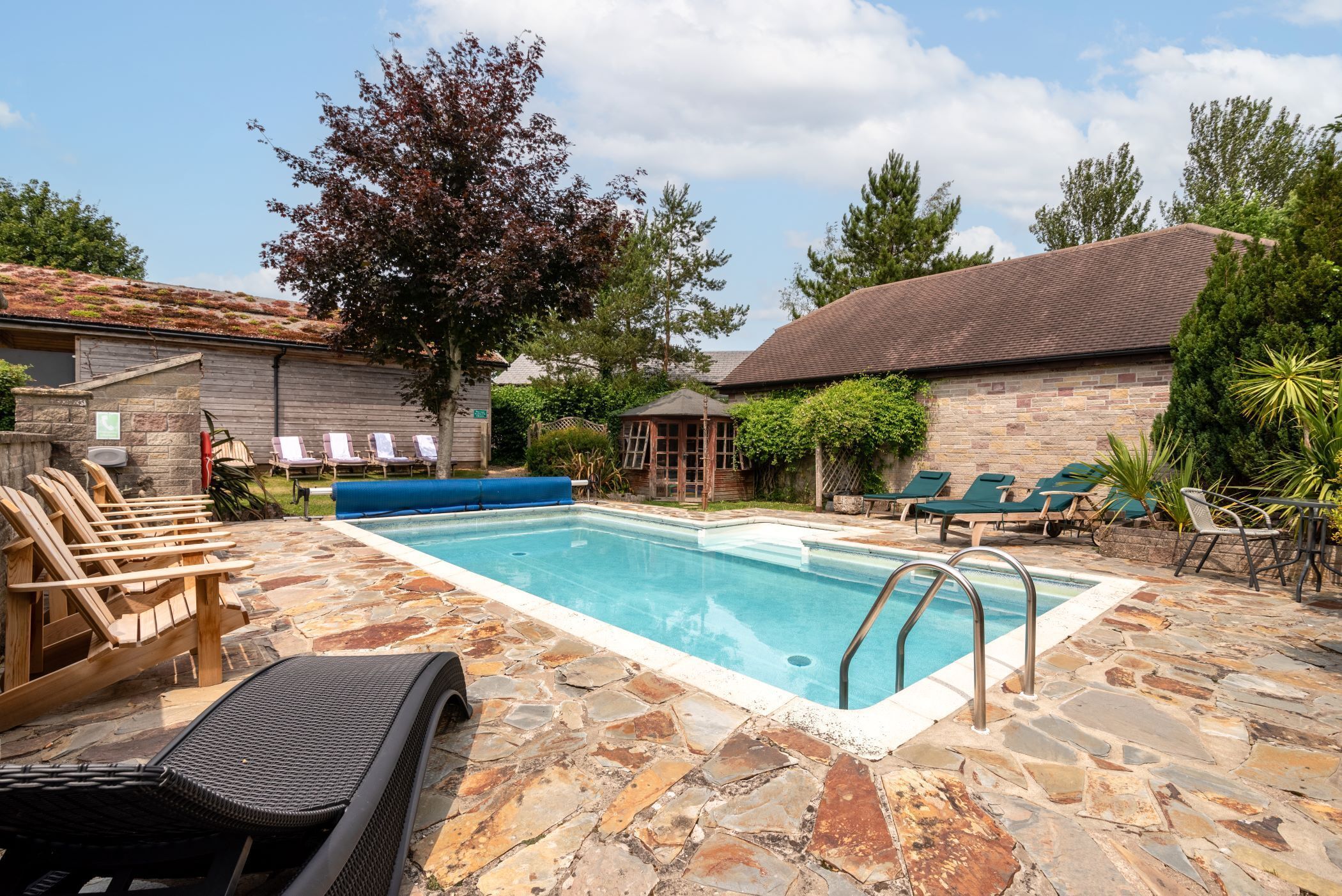 A swimming pool with lounge chairs and a stone patio.