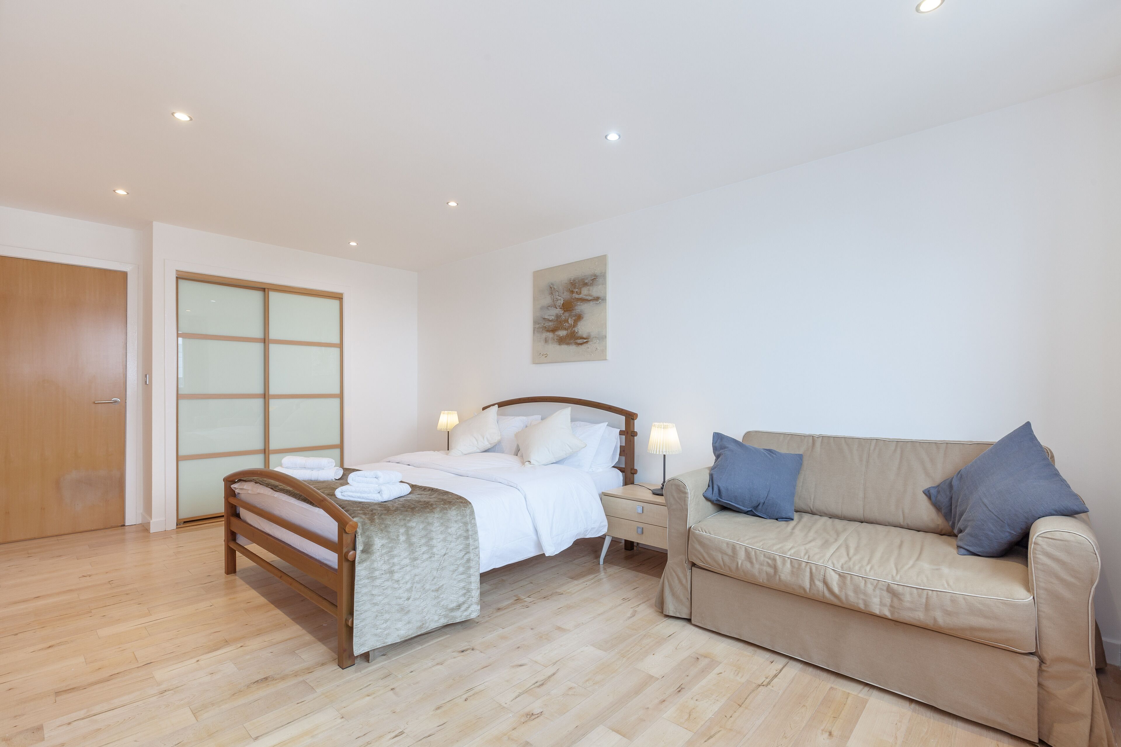 A bedroom with a bed, bedside table, and a sofa.