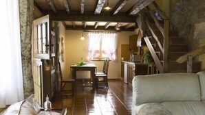Una sala de estar acogedora con un sofá, una zona de comedor con mesa y sillas, y una escalera que sube a un nivel superior.