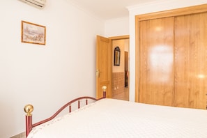 Una camera da letto con un letto, un'armadio in legno, una porta e un quadro appeso al muro.