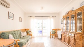 Una sala de estar con sofá, sillas, un aparador de madera y una mesa de comedor.