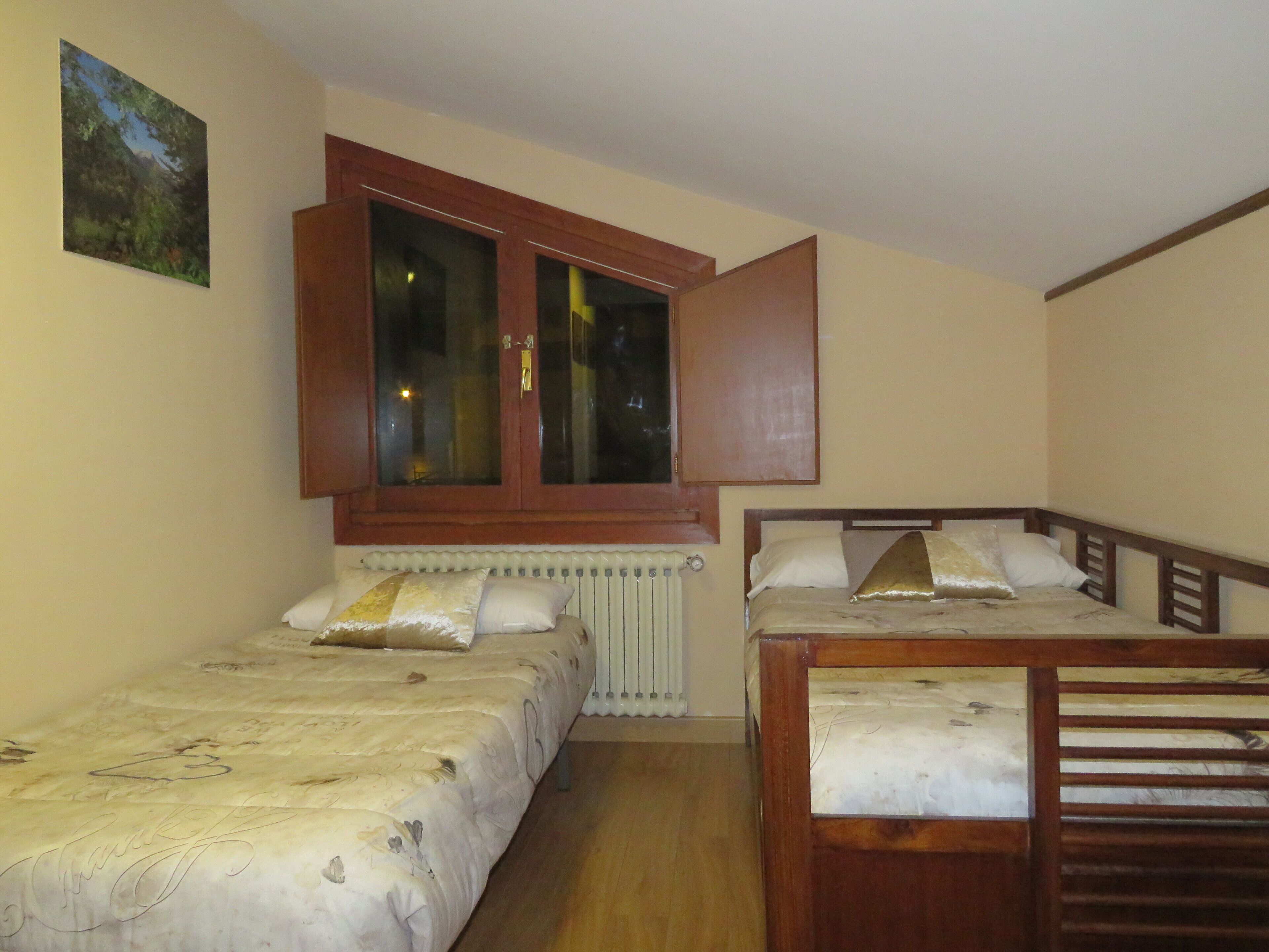 A bedroom with two single beds, a window with a view, and a radiator.