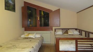 A bedroom with two single beds, a window with a view, and a radiator.