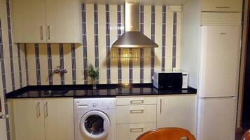 Una cocina compacta equipada con lavadora, microondas y refrigerador.