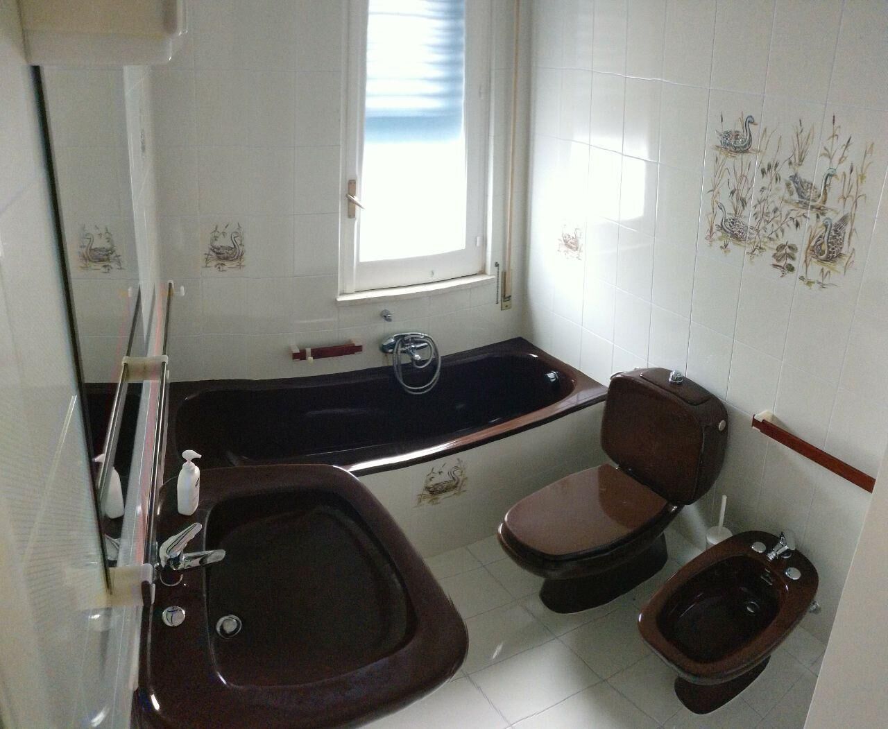 A bathroom with a bathtub, two toilets, and a bidet.
