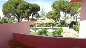 A balcony with two wicker chairs and a small round table, overlooking a residential area with trees and houses. - Villa Rosa - Fontane Bianche - two independent apartments with pool by the sea (Fontane Bianche)