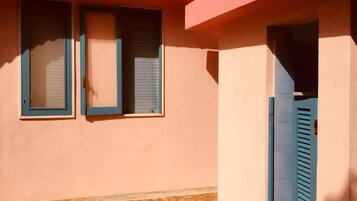 Un edificio con dos ventanas y una puerta, todas con persianas azules.