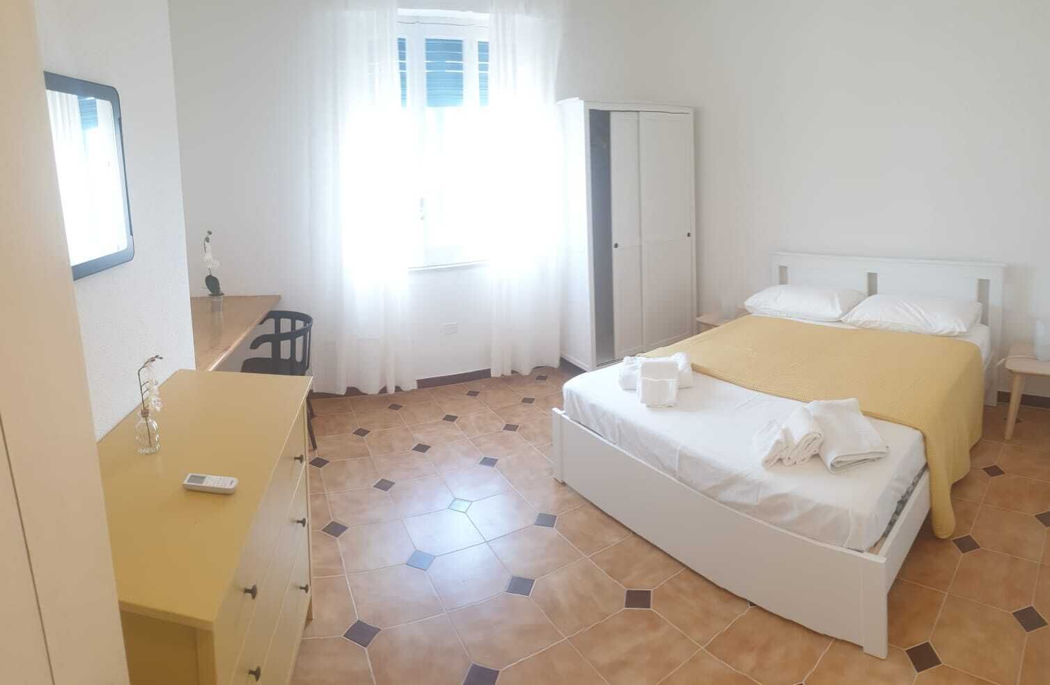 Quarto de hotel com uma cama, uma escrivaninha e uma cadeira.