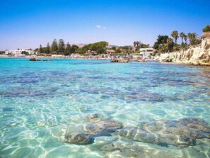 A clear turquoise sea with visible rocks and a sandy beach. - Villa Rosa - Fontane Bianche - two independent apartments with pool by the sea (Fontane Bianche)