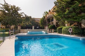 Relax by the rectangular pool surrounded by lush greenery and a fence with a gate.