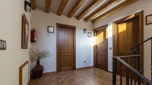 Un pasillo con puertas de madera, piso de baldosas y una escalera con barandilla de madera.