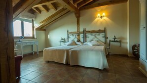 Un dormitorio con techo de madera, una cama con dos almohadas, una mesita de noche y una lámpara.