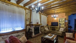 Una sala de estar acogedora con chimenea, vigas de madera y asientos cómodos.