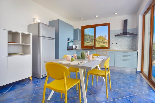 Una cocina moderna con una mesa de comedor, sillas amarillas y vistas al exterior a través de una ventana.
