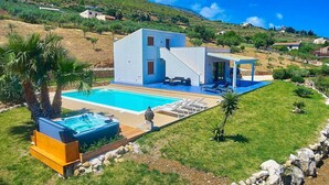 A modern two-story house with a swimming pool, outdoor seating, and a view of the surrounding hills. - Villa Ananda con vista mare, piscina e jacuzzi (Scopello)