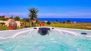 A hot tub with a view of the ocean and a palm tree. - Villa Ananda con vista mare, piscina e jacuzzi (Scopello)