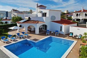Una piscina con sillas de descanso y una terraza.