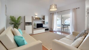 A modern living room with a sofa, TV, and a plant.