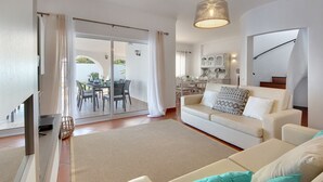 A living room with a sofa, a TV, and a dining area with a table and chairs.