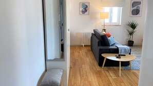 A modern living room with a sofa, a small table, and a potted plant. - Riverview Bright Studio @Graça. New Deco 2023! (Lisboa)