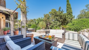 A patio area with wicker furniture, a glass-top table with food, and potted plants.