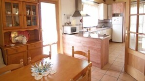 A kitchen with wooden cabinets, a dining table, and a central island. - Casa Javier for 4 people (Rodellar)