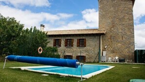 A stone building with a swimming pool and a blue slide.
