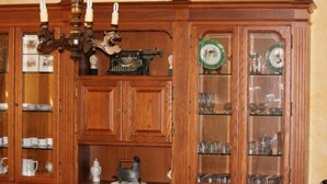 A wooden cabinet with glass doors containing various items like cups, plates, and a decorative object.