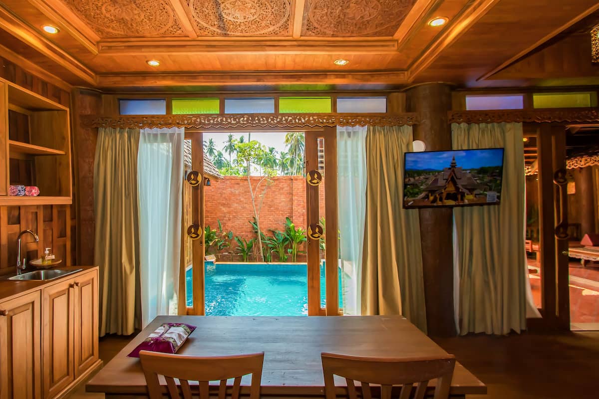 A room with a pool view, wooden cabinets, and a TV on the wall.