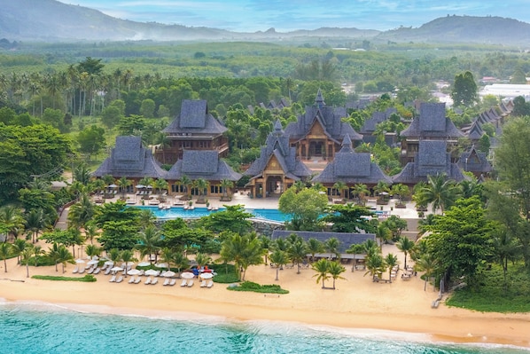 A resort with multiple buildings, a swimming pool, and a beach area.