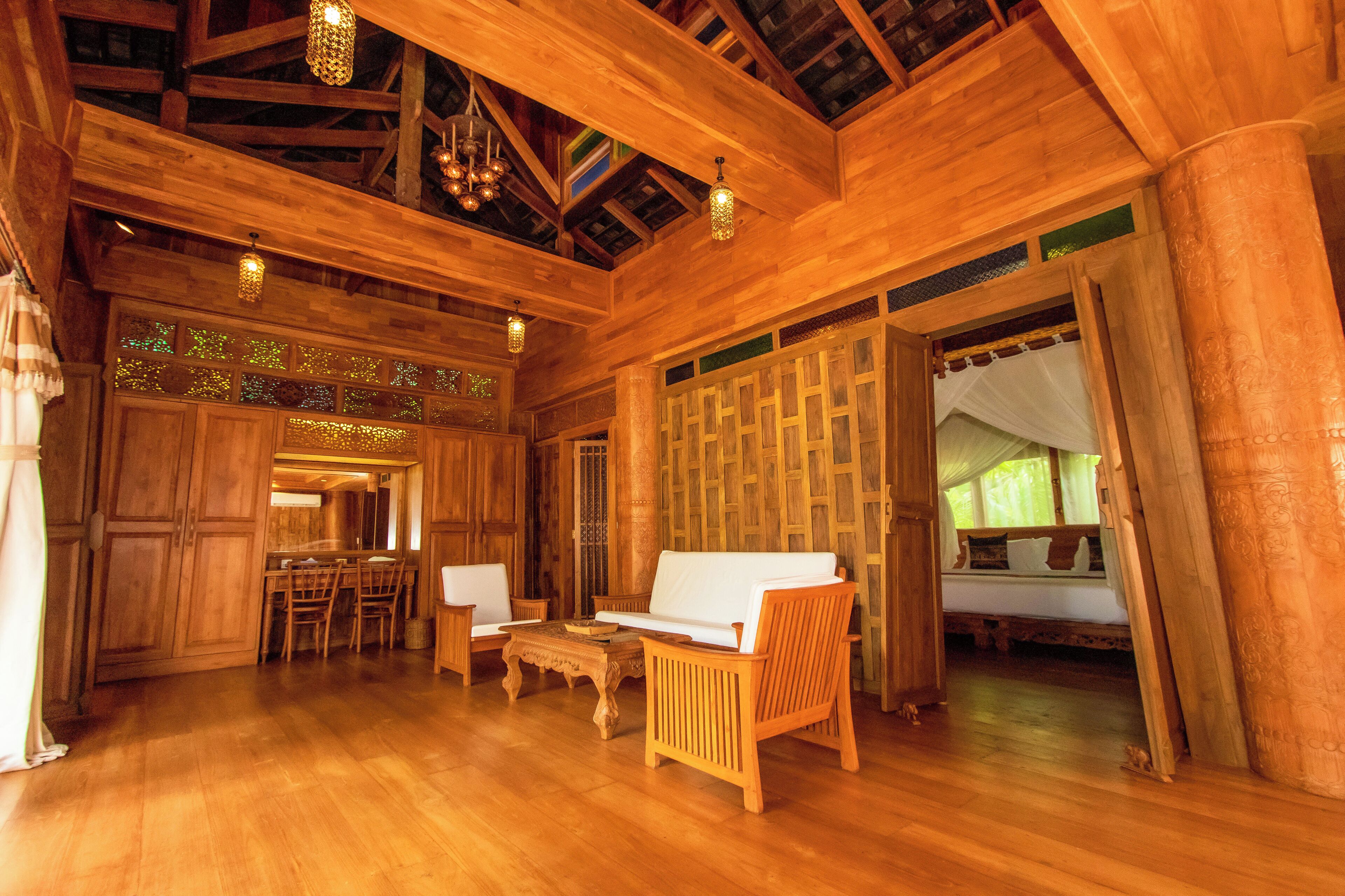 A spacious wooden interior with a dining area, a sofa, and a bed with a canopy.