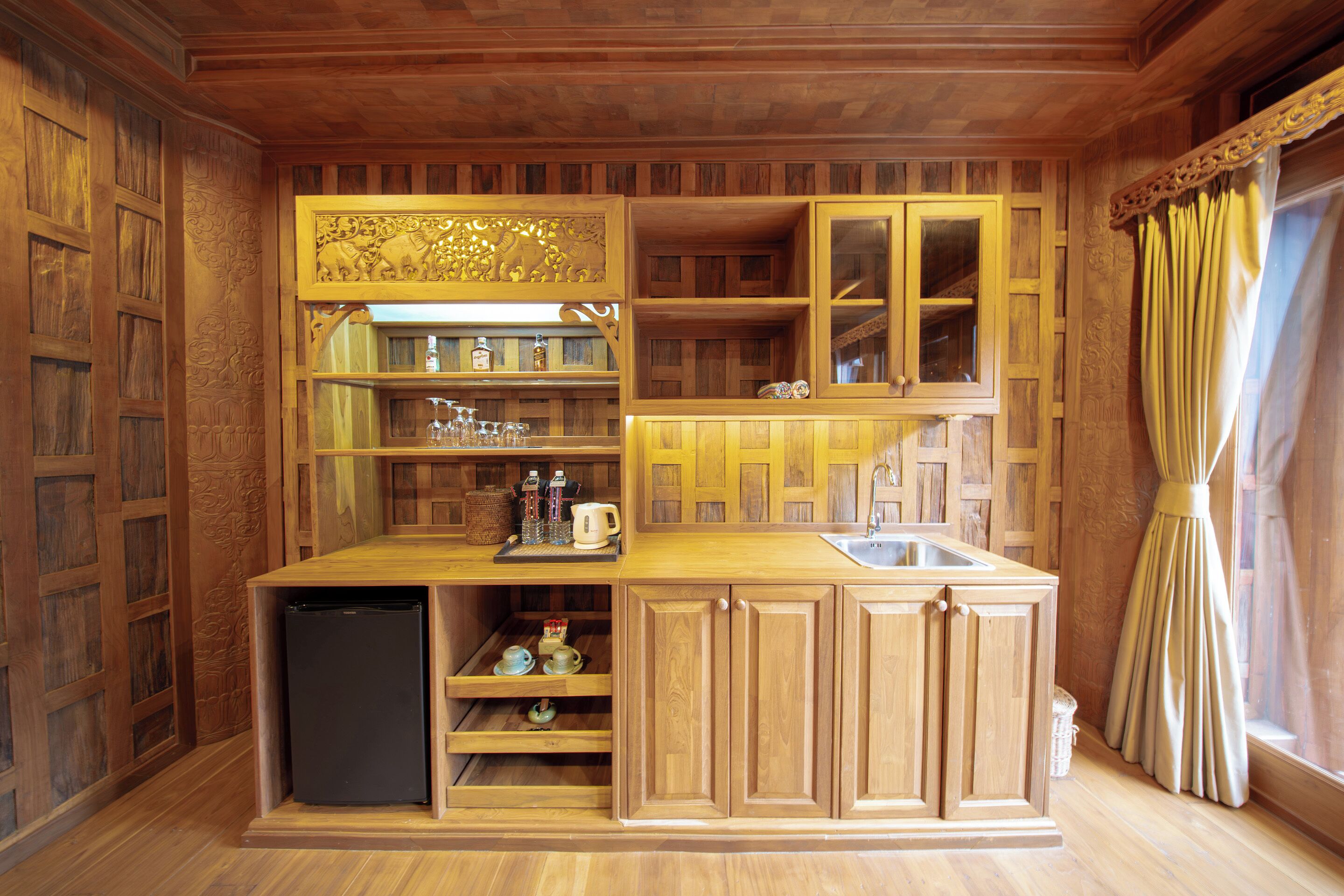 A compact kitchen with wooden cabinetry, a built-in refrigerator, and a sink.