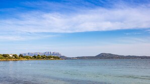 A coastal landscape with clear waters, distant mountains, and a shoreline with buildings. - Villa Amar 4, Emma Villas (Pittulongu)