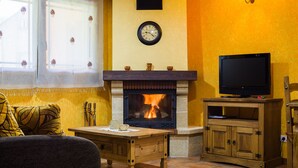 Ein gemütliches Wohnzimmer mit Kamin, Fernseher und einer Wanduhr.