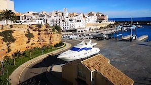 A coastal town with a marina, white buildings, and a large yacht docked at the pier.