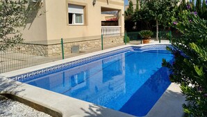 A swimming pool with a tiled edge, a balcony with a railing, and a building with a beige facade.