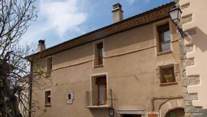 A two-story building with a stone facade, a small balcony, and a wooden door.