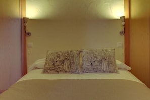 Cozy retreat with a single bed, adorned with a patterned pillow and a plain white pillow, and a wooden headboard.