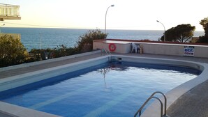 A swimming pool with a view of the sea, a lifebuoy, and a no swimming sign. - Apartment facing the sea with pool and 2 bedrooms (Salou)