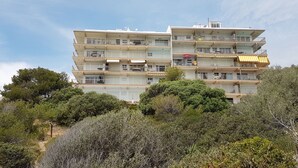 A multi-story residential building with balconies, surrounded by dense shrubbery. - Apartment facing the sea with pool and 2 bedrooms (Salou)